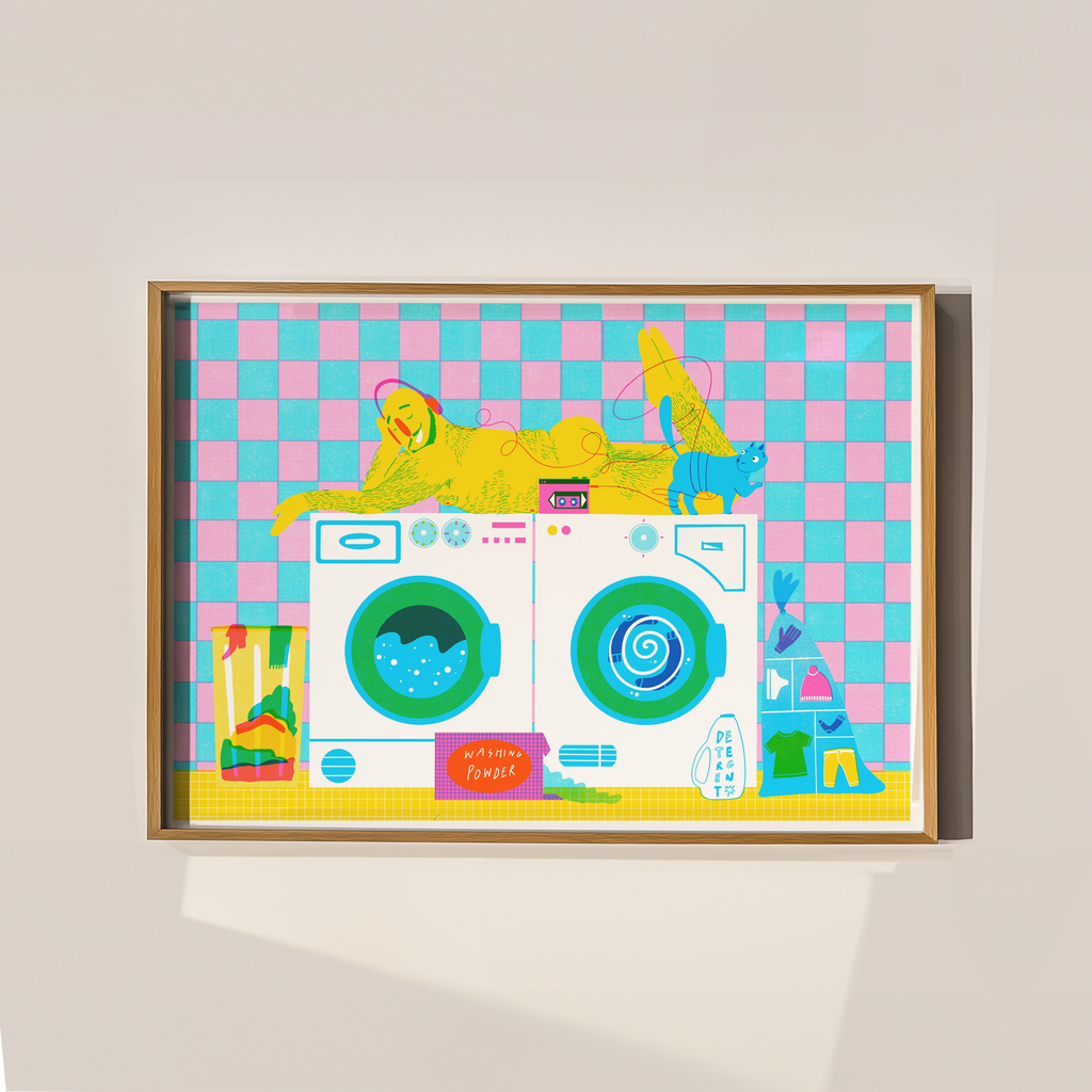 Colorful framed artwork of a hairy man lying on top of a washing machine on a checkered background, with a cat and washing machines.