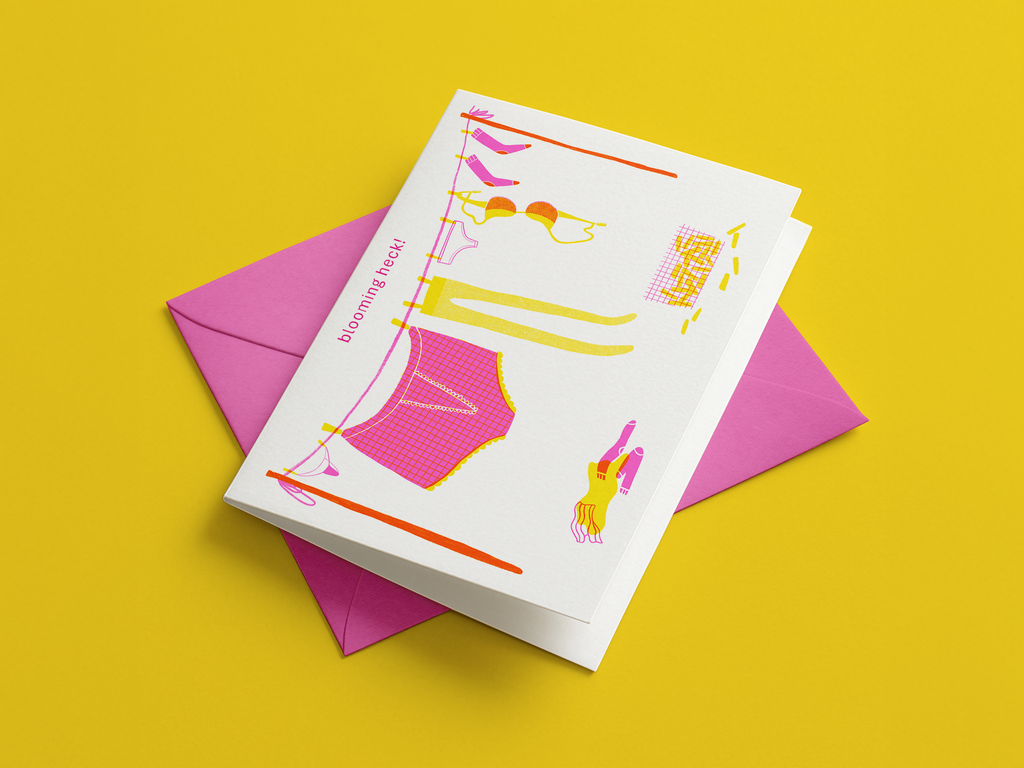 Greeting card with colorful illustrations of underwear and a big pair of pants and laundry on a clothesline with a pink envelope against a yellow background.