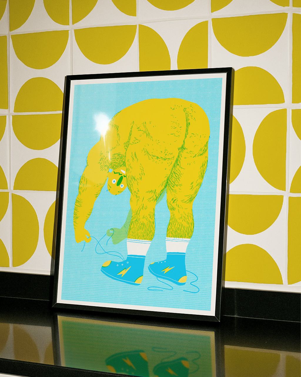 Framed artwork of a yellow hairy man with blue shoes on a light blue background, against a yellow and white patterned wall, bending over to tie shoes with bum on show.