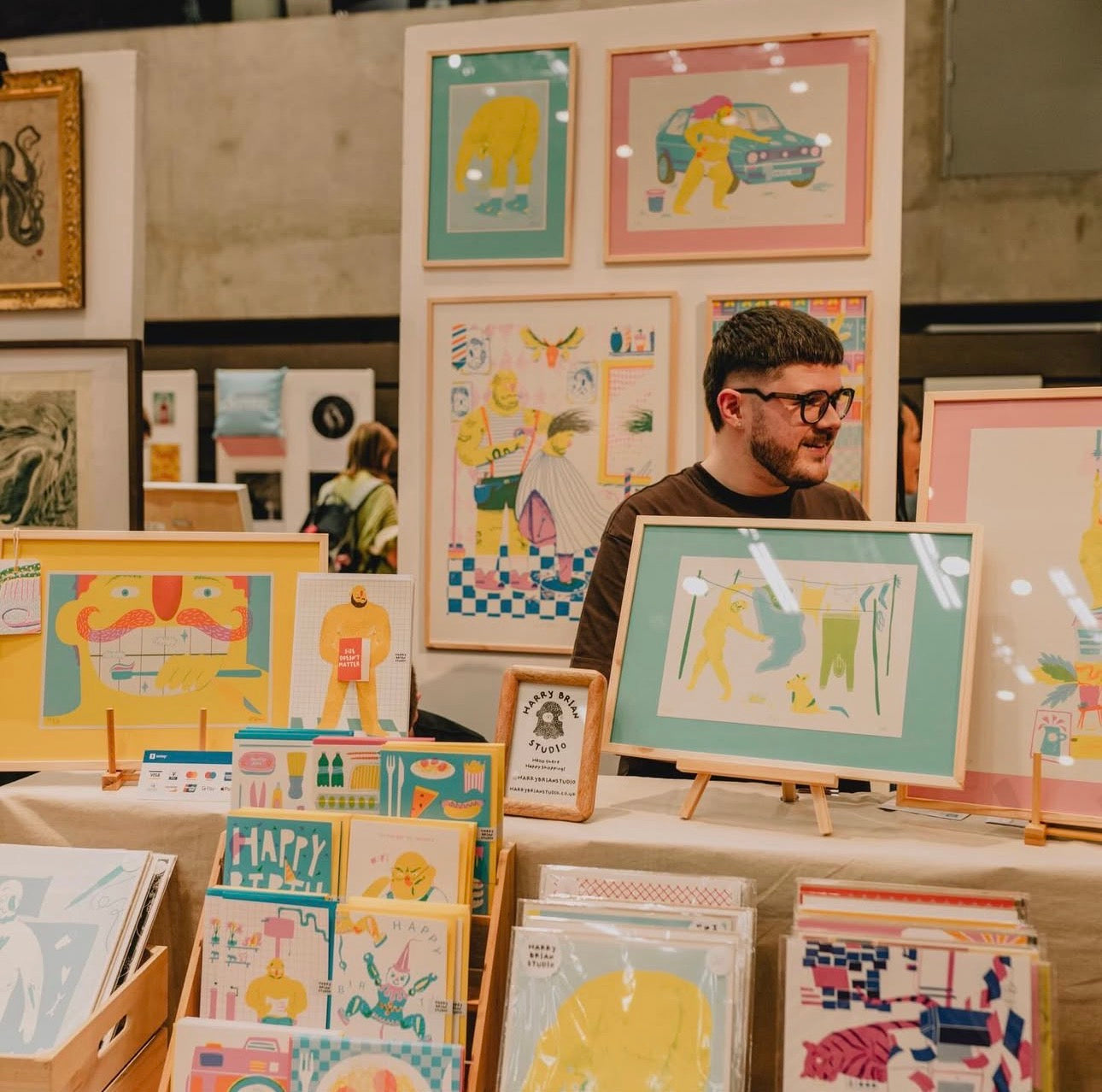 Harry Brian Studio, action shot selling at Nottingham Contemporary Print Fair, stood behind his stall of risograph prints and greeting cards.