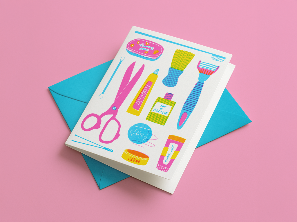 Greeting card with colorful illustrations of toiletries and beauty products on a pink background with bright sky blue envelope.
